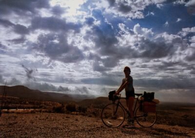 Glen Woodfin Stops on His Bicycle Route to Appreciate the Sun Shining Through the Billowy Clouds of West Texas